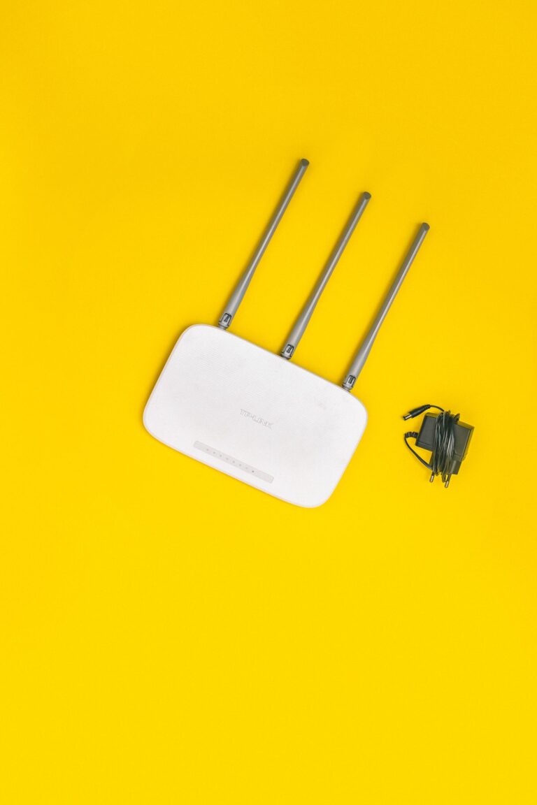 A white Wi-Fi router with antennas on a yellow background