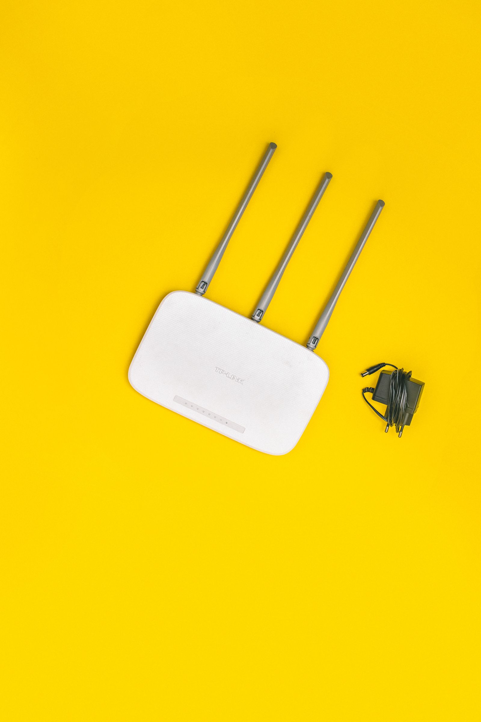 A white Wi-Fi router with antennas on a yellow background